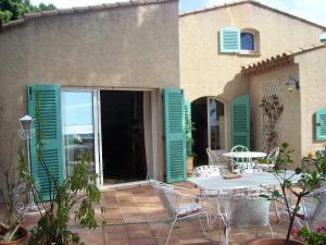 een patio met een tafel en stoelen voor een huis bij Villa de 4 chambres avec vue sur la mer piscine privee et jardin amenage a Hyeres a 2 km de la plage in Hyères