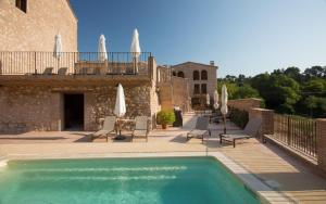 a swimming pool in front of a building with umbrellas at Cozy apartment in Orpí with pool in Orpí