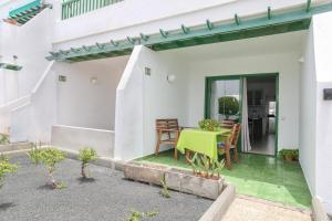 a white house with a green table and chairs at One bedroom apartement at Tias 500 m away from the beach with shared pool furnished terrace and wifi in Tías