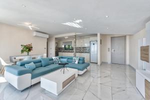 a living room with a blue couch and a kitchen at Mandala Seafront Suites in Laganas