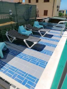 une rangée de chaises longues et une piscine dans l'établissement 4 bedrooms villa with sea view private pool and furnished terrace at Alcamo Marina, à Alcamo Marina