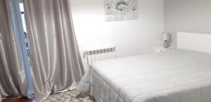 ein weißes Schlafzimmer mit einem Bett und einem Fenster in der Unterkunft Lourenço House in Póvoa de Varzim
