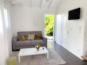 a living room with a couch and a table at Appartement confortable au Moule 60 m² avec piscine privée in Le Moule