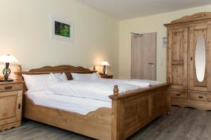 ein Schlafzimmer mit einem großen Holzbett mit weißer Bettwäsche in der Unterkunft Landhotel Altes Pfarrhaus in Bilzingsleben