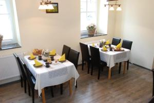 a dining room with white tables and black chairs at Landhotel Altes Pfarrhaus in Bilzingsleben