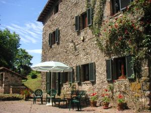 a stone building with a table and an umbrella at 3 bedrooms villa with private pool furnished garden and wifi at Barga in Barga