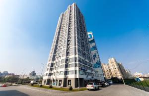 a tall white building with cars parked in a parking lot at Люкс в ЖК Лебединый, Харьковская, Позняки in Kyiv
