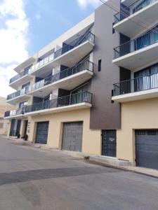 an apartment building with four garage doors on a street at 2 bedrooms appartement with sea view furnished terrace and wifi at Ghajnsielem in Għajnsielem