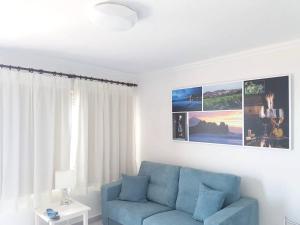 a living room with a blue couch and a window at One bedroom appartement with sea view shared pool and furnished terrace at Tacoronte 4 km away from the beach in Tacoronte