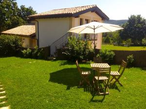 a table and chairs with an umbrella in front of a house at El Mirador de Casa Guareña in Villabáscones de Sotoscueva