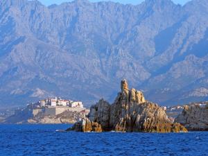 a castle on a rock in the middle of the water at Maison de Vacances Enchantée à Calvi avec Vue sur Mer et Montagne in Calvi
