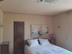a bedroom with a bed with white pillows and a painting at Maison de Vacances Enchantée à Calvi avec Vue sur Mer et Montagne in Calvi +20 photos