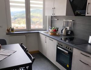 a kitchen with a stove and a table and a window at Ferienwohnung am Hirschkopf in Baiersbronn