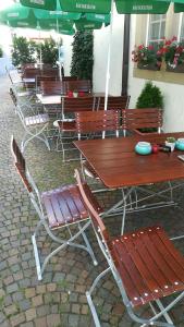 una fila de mesas y sillas de madera con sombrillas en Gasthof Stadtschänke, en Großbottwar