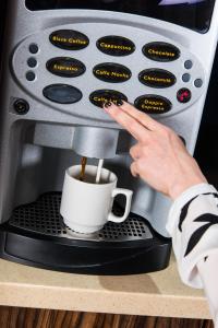 
a person holding a coffee cup in front of a microwave at Eden Plaza Kensington in London
