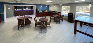 a dining room with tables and chairs and a kitchen at Baymont by Wyndham Adairsville in Adairsville