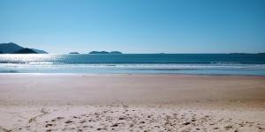 a beach with footprints in the sand and the ocean at Casa na Praia da Pinheira in Palhoça