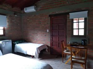 a bedroom with two beds and a table and a window at El Indalo La Calderilla in Salta