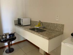 Una encimera de cocina con fregadero y microondas. en Flat à beira mar em João Pessoa -Pacific Flat, en João Pessoa