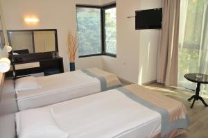 a bedroom with two beds and a television and a table at Hotel Burgas Free University in Burgas