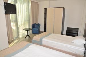 a hotel room with two beds and a tv and a chair at Hotel Burgas Free University in Burgas