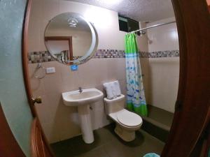 a bathroom with a sink and a toilet and a mirror at Hostal Dulce Amanecer in Baños