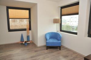 a living room with a blue chair and a window at Hotel Burgas Free University in Burgas