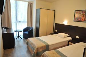 a hotel room with two beds and a chair at Hotel Burgas Free University in Burgas