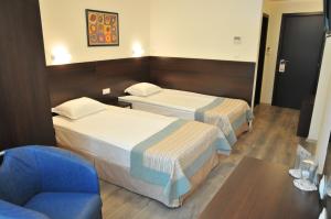 a hotel room with two beds and a chair at Hotel Burgas Free University in Burgas