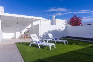 drie witte stoelen op het gras in een tuin bij Rooms & Suites Princesa Leticia in Puerto del Carmen