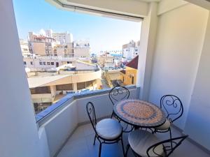 a balcony with a table and chairs and a large window at Vasilo Court Seaview City Apartment in Larnaka