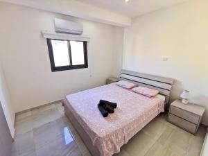 sypialnia z łóżkiem z różową pościelą i oknem w obiekcie Vasilo Court Seaview City Apartment w Larnace