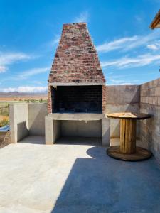 a brick fireplace with a table on a patio at Die Kliphuisie in Oudtshoorn