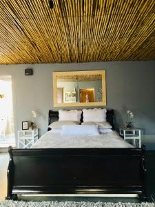 a bedroom with a large bed with a wooden ceiling at Die Kliphuisie in Oudtshoorn