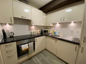 una cucina con armadi bianchi e lavandino di Cosy Riverside Apartment - FREE PARKING a York