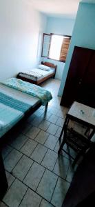 a room with two beds and a table in it at Pousada Minas Gerais in Tramandaí
