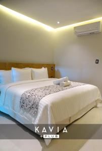 een slaapkamer met een groot bed met witte lakens bij Hotel Kavia Plus in Cancun