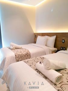 um quarto de hotel com duas camas com lençóis brancos em Hotel Kavia Plus em Cancún