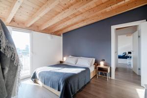 - une chambre avec un lit et un mur bleu dans l'établissement White Attic - by MyHomeInComo, à Camnago Volta