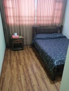 een slaapkamer met een bed en een houten vloer bij Hotel Consuelo in Tunja