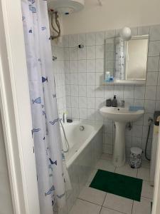 a bathroom with a tub and a sink and a shower curtain at Négy évszak Apartman- Tapolca in Tapolca