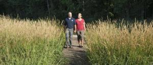 un hombre y una mujer caminando por un camino a través de la hierba alta en Lake Orchard Farm Retreat, en Sheboygan