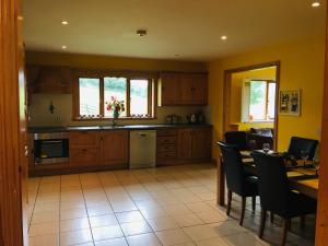 a kitchen with wooden cabinets and a table and chairs at 4 Bedrooms with stunning Lake View Drumcoura Lake Resort beside Saloon & equestrian Centre, Lakes & Forest in Ballinamore