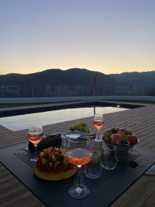 a table with two glasses of wine and a plate of fruit at Maximos Luxury Villa with Pool -BREAKBOOKING-CY in Limassol