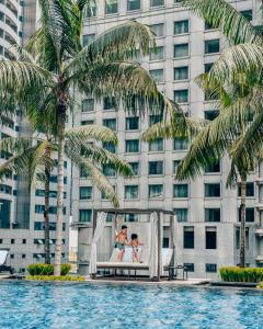 a bride and groom in a wedding dress in front of a hotel pool at Grand Hyatt Kuala Lumpur in Kuala Lumpur