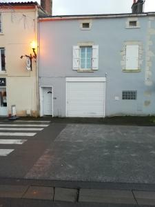 un edificio blanco con dos puertas de garaje y una calle en Joli appartement, 1 chambre, au cœur de Mouilleron St Germain en Mouilleron-en-Pareds