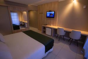 a hotel room with a bed and a desk and a television at Hotel Águas Claras in Santa Cruz do Sul