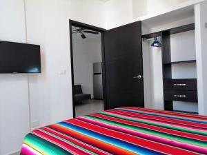 a bedroom with a bed with a colorful striped blanket at Condo Kiaraluna in Playa del Carmen