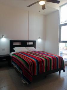 a bedroom with a bed with a colorful blanket on it at Condo Kiaraluna in Playa del Carmen