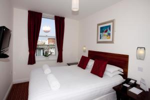 a bedroom with a white bed with red pillows and a window at Park Central Hotel in Bournemouth